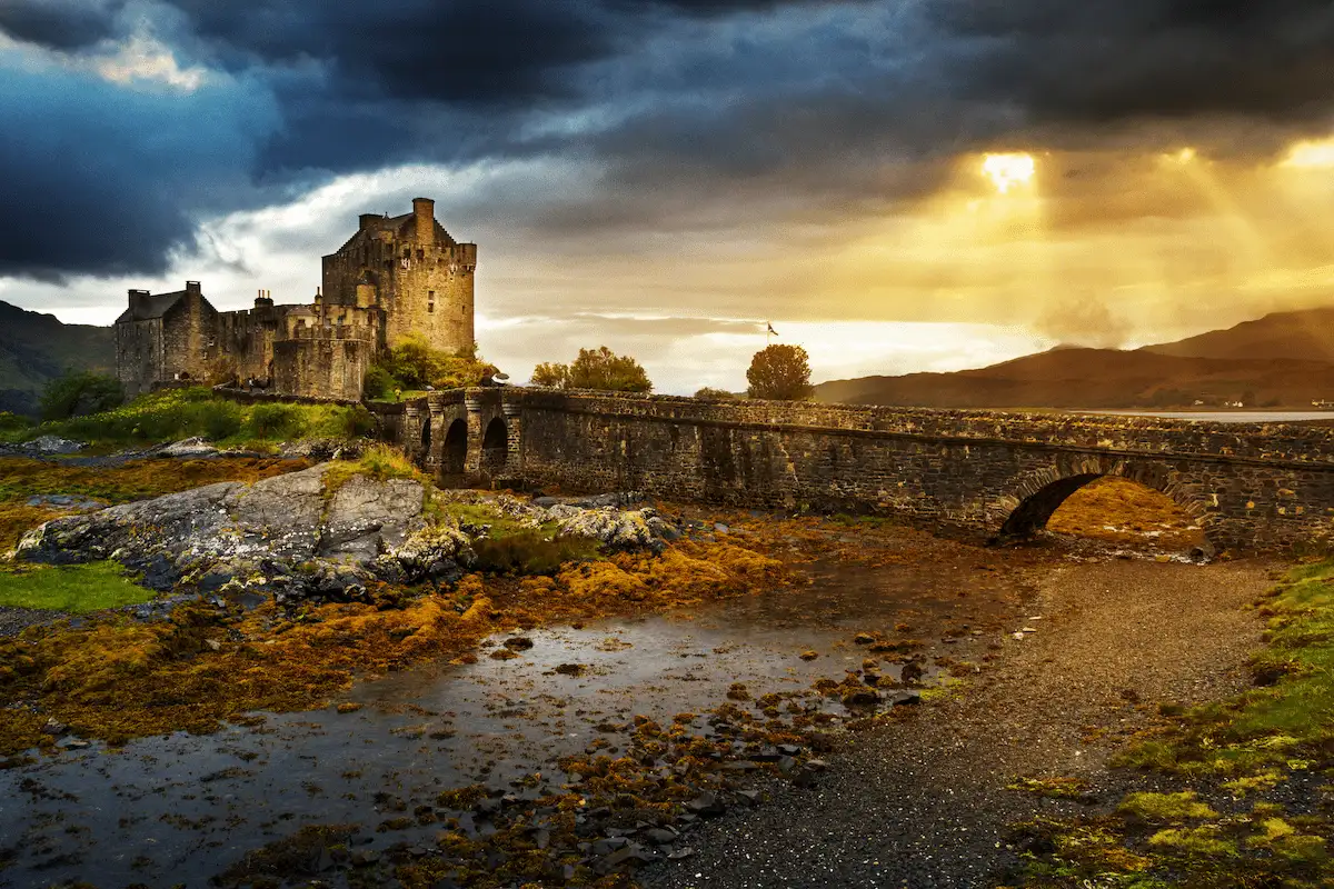Eilean Donan Castle and stone bridge under dramatic sunset light and stormy clouds. Isle of Skye, Scotland.