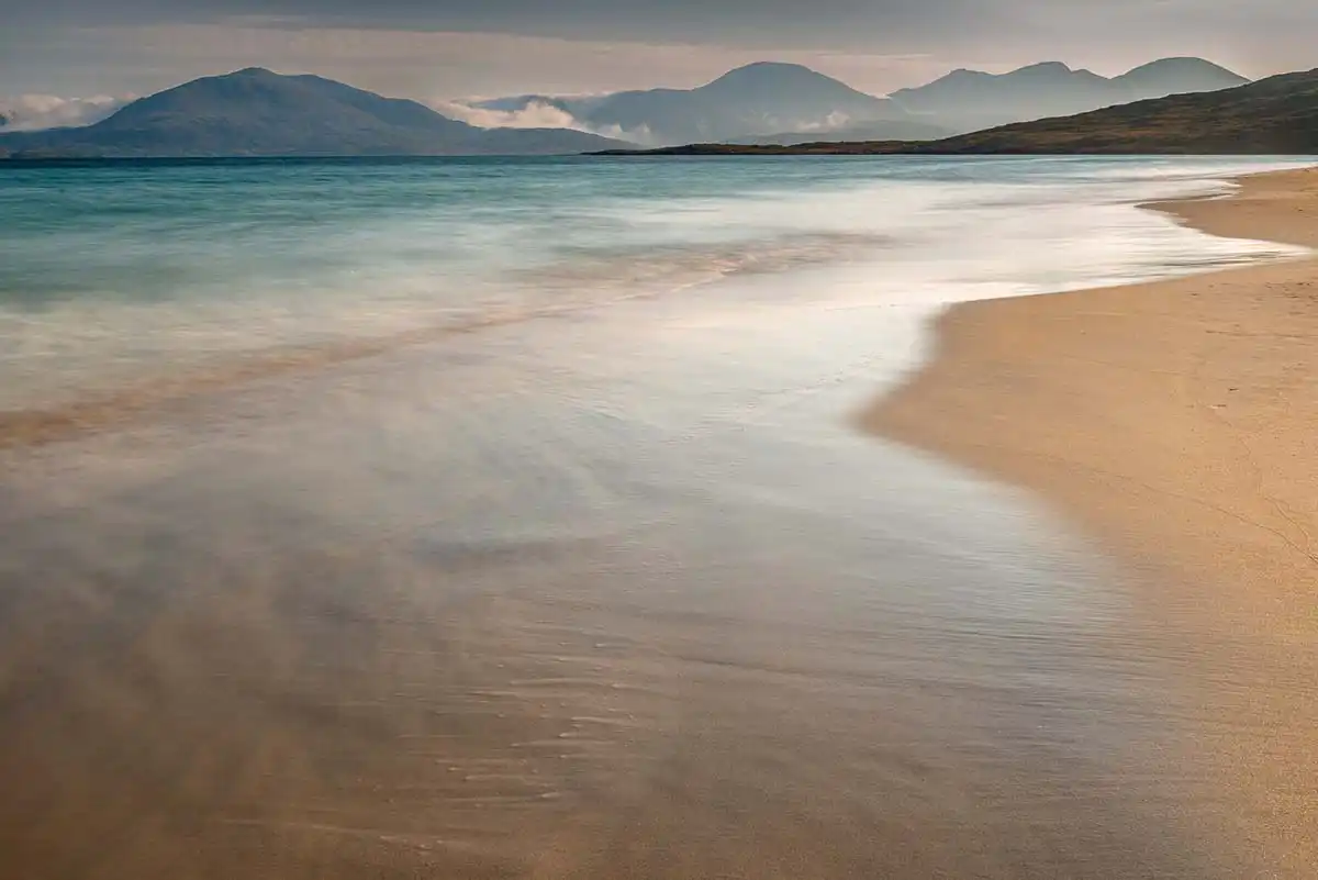 Turquoise water sweeping across the white sands of Luskentyre Beach beneath the mountains of South Harris.